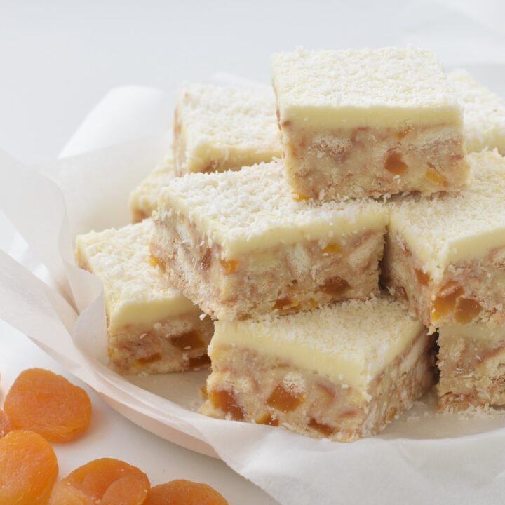 Apricot Coconut Slice squares stacked on a plate.