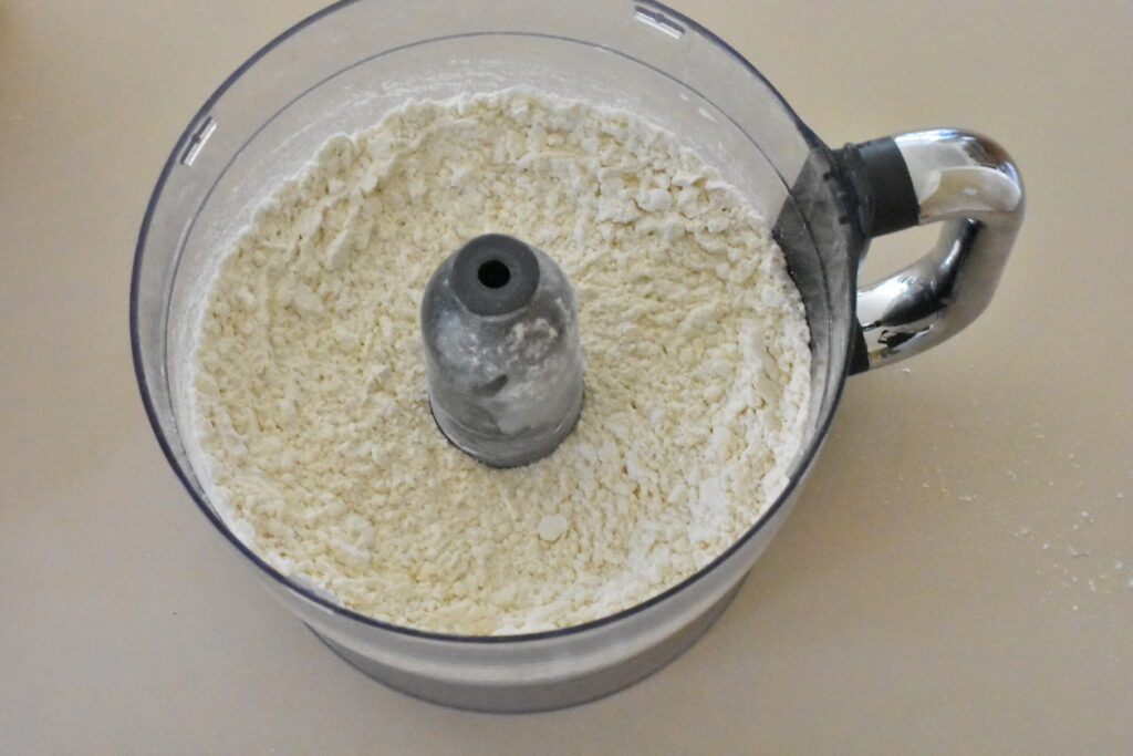 Showing fine breadcrumbs texture of flour, butter, sugar and salt in the food processor.