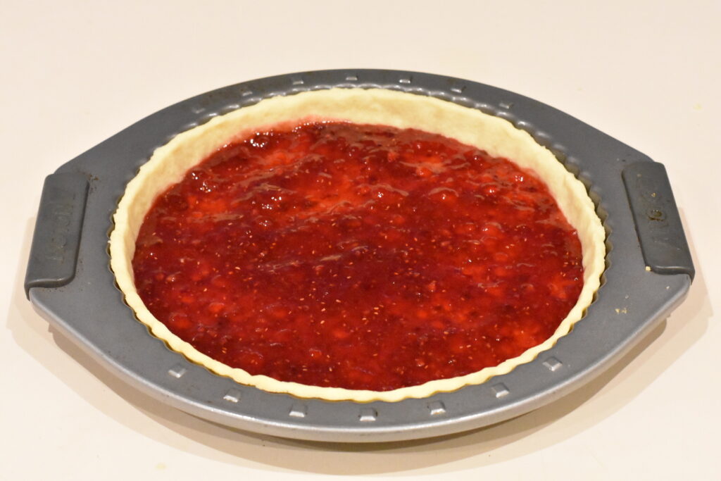Raspberry filling spread over baked tart shell.