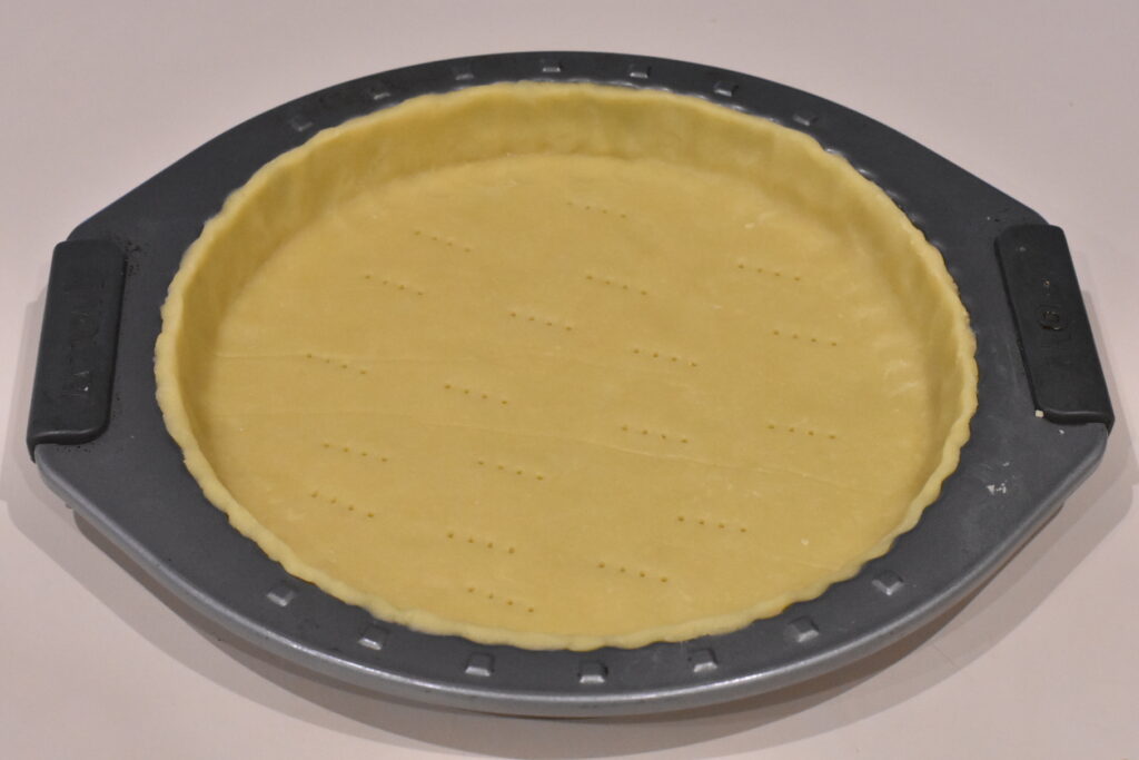 Tart dough pressed into tart tin with edges trimmed.