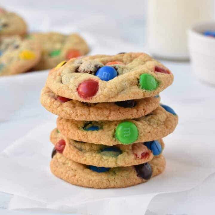 Stack of M&M cookies on baking paper.
